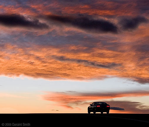 A Ford Mustang heading into the sunset, on Highway 68 south of Taos, New Mexico 