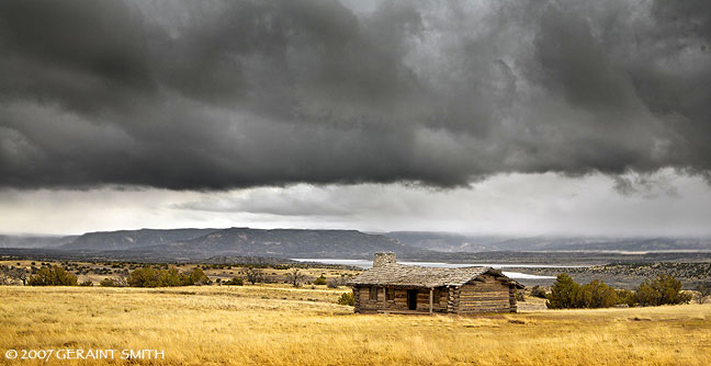 Log cabin, Abiquiu Lake and approaching spring storm from Ghost Ranch, New Mexico
