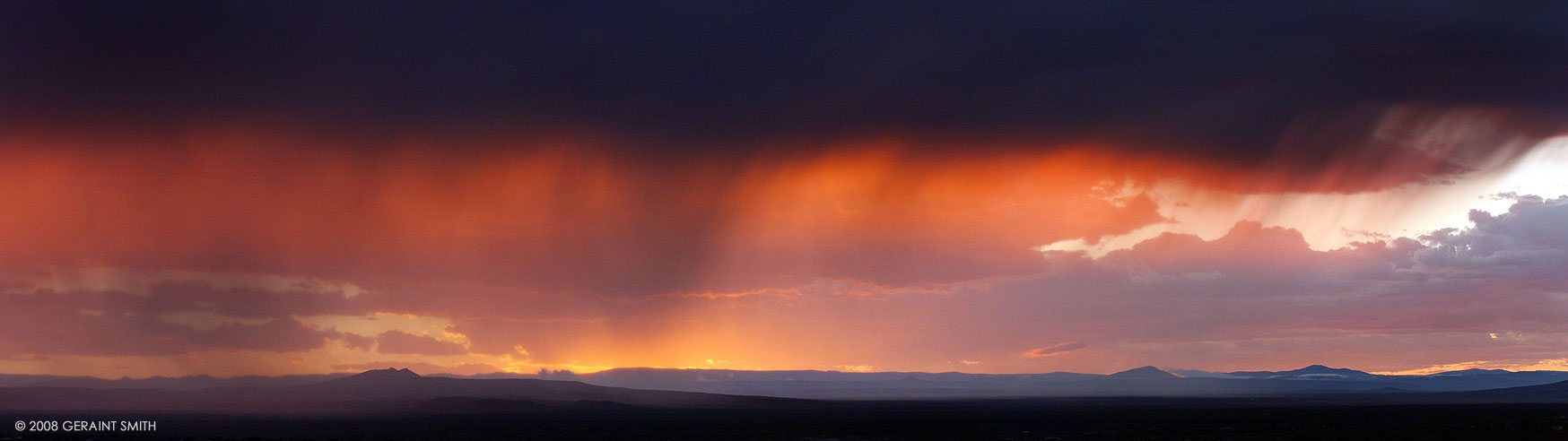 A Taos sunset across the mesa throught the rain