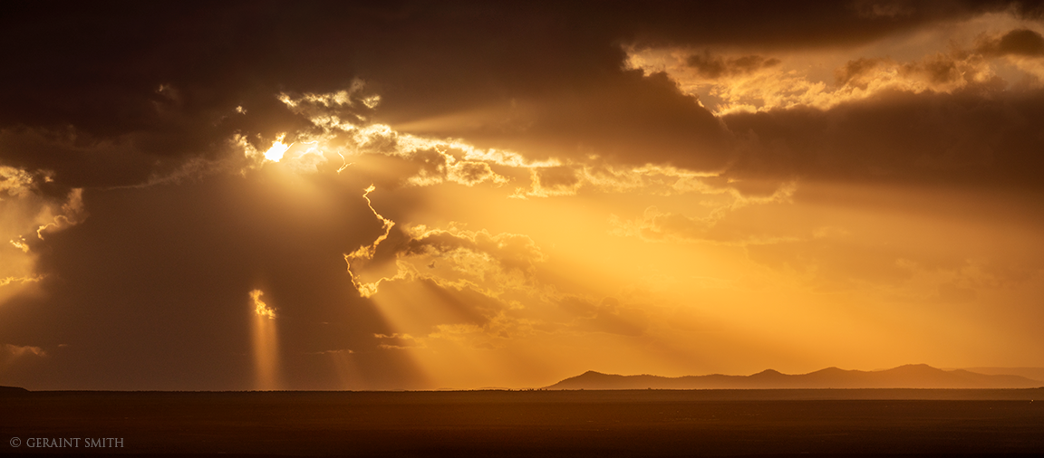 Taos Plateau, sunset rays with storm clouds brewing. 