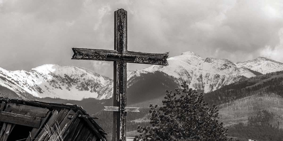 Wooden cross with mountain peaks