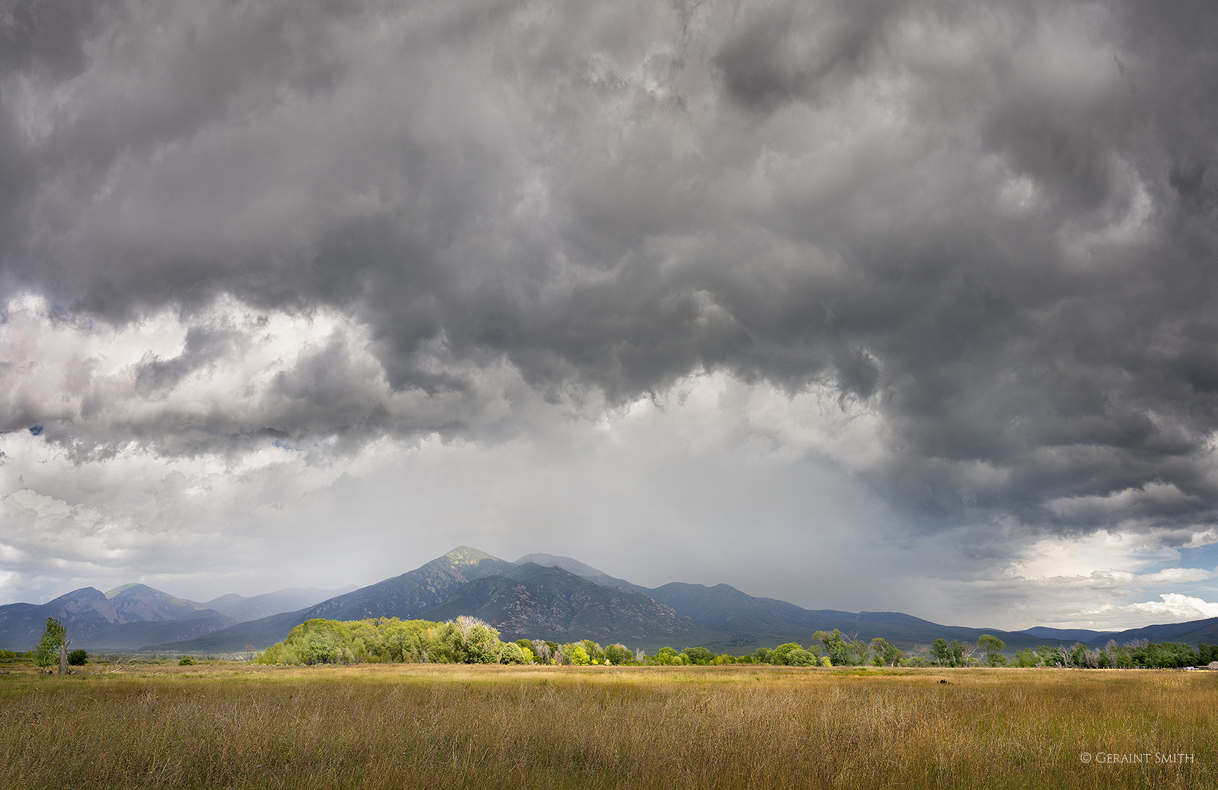Storm across the meadow to Taos Mountain